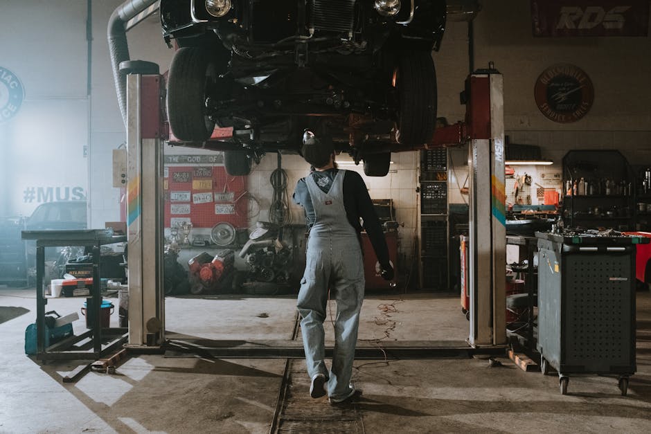 Automobile mechanic fixing a car in a repair garage, focus on service and repair work